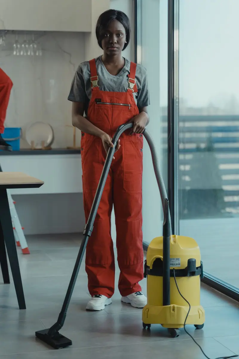 A uniformed Olivers cleaner vacuuming an office floor